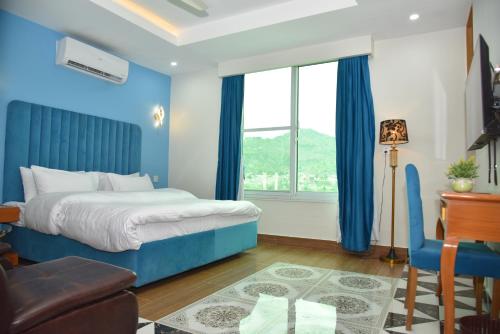 a bedroom with blue walls and a bed and a desk at Bridge Residency River View Hotel Near Bridge,201 in Muzaffarabad