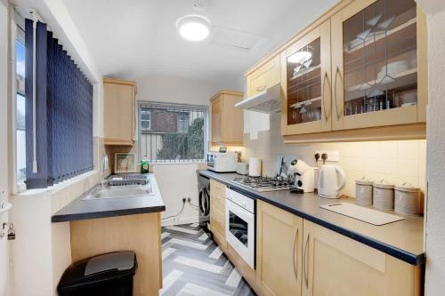 a kitchen with wooden cabinets and a counter top at 2-Bedroom Stay with Free Wi-Fi Near Town Centre in Darlington