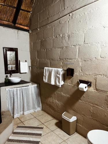 a bathroom with a sink and a brick wall at Victoria Falls Backpackers Lodge in Victoria Falls