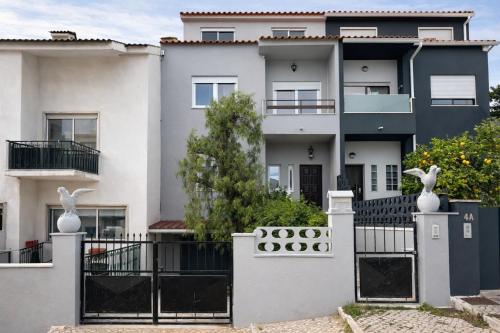a white house with a black fence andanimal statues at Charneca Mar & Sol in Charneca