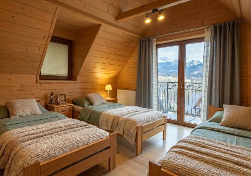 a bedroom with two beds and a balcony with mountains at Hole in Zakopane