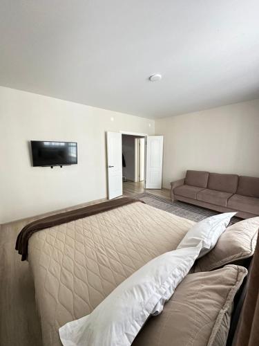 a bedroom with a bed and a couch in it at Apartment on Satpayeva in Ustʼ-Kamenogorsk