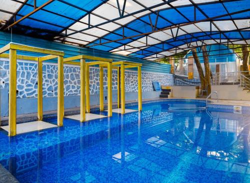 a large swimming pool with yellow poles in a building at Blue Park Nature Resort in Mahabaleshwar