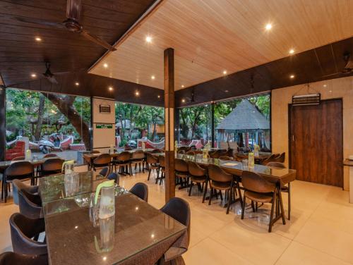 a restaurant with tables and chairs and a large window at Blue Park Nature Resort in Mahabaleshwar