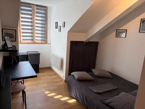 a bedroom with a bed and a desk and a window at Studio neuf in Barcelonnette