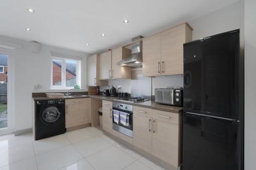 a kitchen with wooden cabinets and a black refrigerator at New! Spacious Retreat for 10 Perfect for Families! in Bowburn