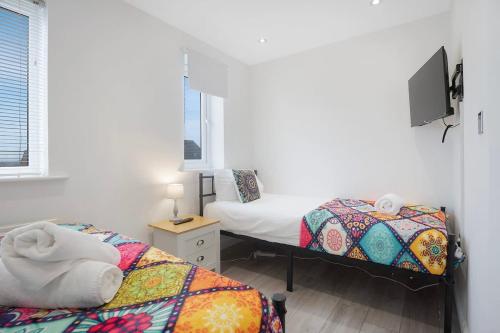 a bedroom with two beds and a tv on the wall at New! Spacious Retreat for 10 Perfect for Families! in Bowburn