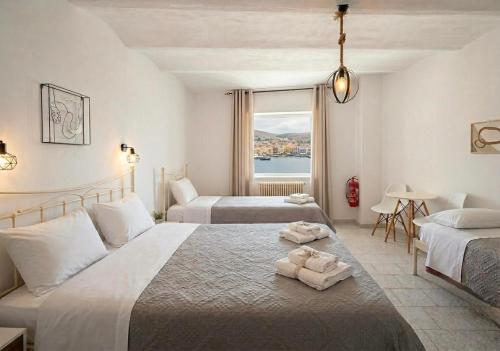 a hotel room with two beds and a window at Casa di Syrii in Ermoupoli
