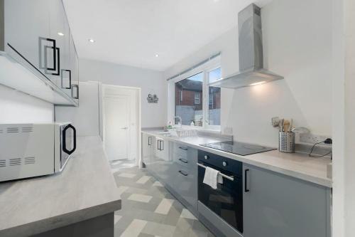 a white kitchen with a stove and a sink at Spacious 4BR on Leafield Rd in Darlington