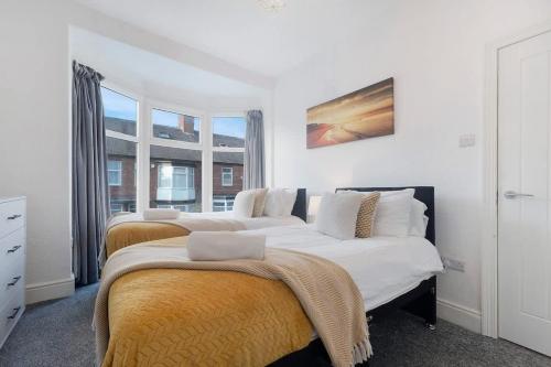 two beds in a room with white walls and windows at Spacious 4BR on Leafield Rd in Darlington