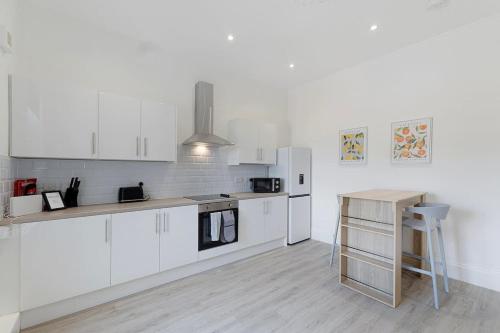 a white kitchen with white cabinets and a table at Spacious! 6BR in Beach Road in South Shields