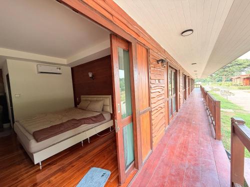 a bedroom with a bed on a wooden floor at โอโซนริมน้ำเขาใหญ่ in Ban Pang Kae