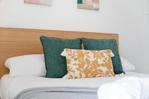 a bed with green pillows and a wooden headboard at New! 4BR in Durham Road in Annfield Plain