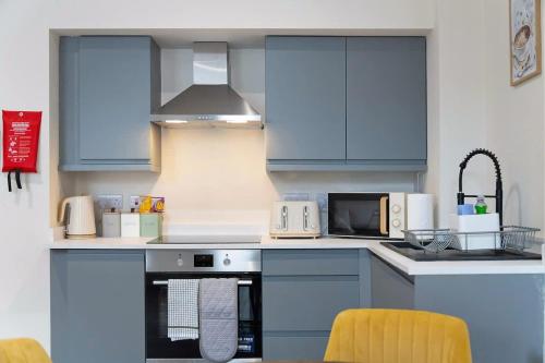 a kitchen with blue cabinets and a stove top oven at Flat2 2BR in Horsemarket in Barnard Castle