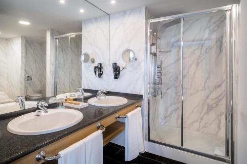 a bathroom with two sinks and a shower at Occidental Atenea Mar - Adults Only in Barcelona