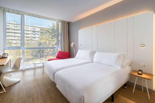 a large white bed in a room with a large window at Occidental Atenea Mar - Adults Only in Barcelona