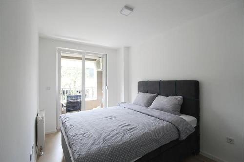 a bedroom with a large bed with white sheets and a window at Apartman Dijamant in Sarajevo
