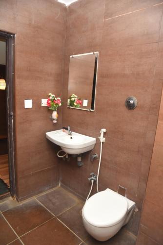 a bathroom with a sink and a toilet and a mirror at Rd HOTEL ERODE ROAD in Perundurai