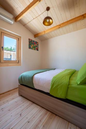 a bedroom with a bed with green sheets and a window at Atessa Escapes in Atessa