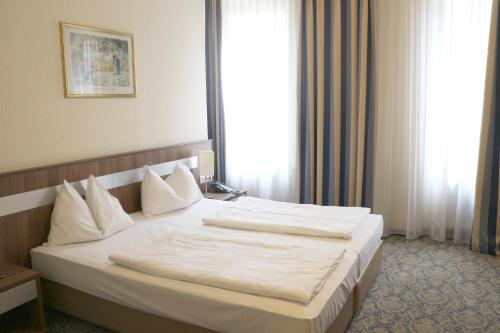 a bedroom with a large bed with white sheets and pillows at Hotel Carina in Vienna