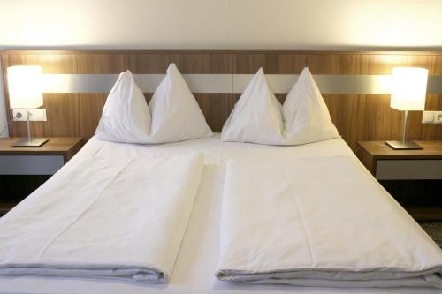 a large white bed with four pillows on it at Hotel Carina in Vienna