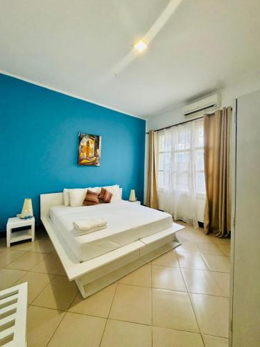 a bedroom with a large white bed in a blue wall at We Call it Home - Bububu Villa in Mtoni