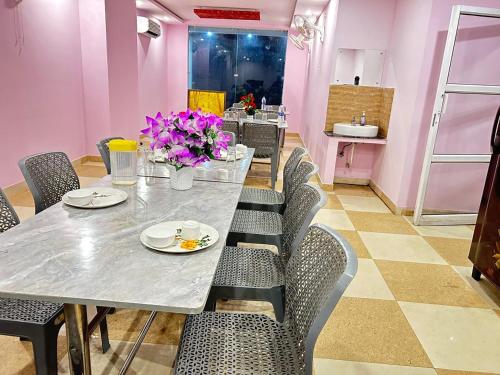 a dining room with a table and chairs with purple flowers at Hotel Exotica Haridwar in Rāiwāla
