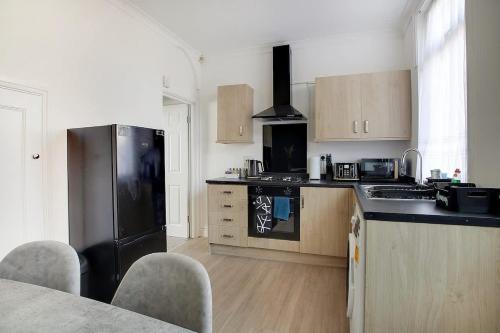 a kitchen with a black refrigerator and wooden cabinets at Stylish 3-Bedroom Oasis in Darlington, Sleeps 5 in Darlington