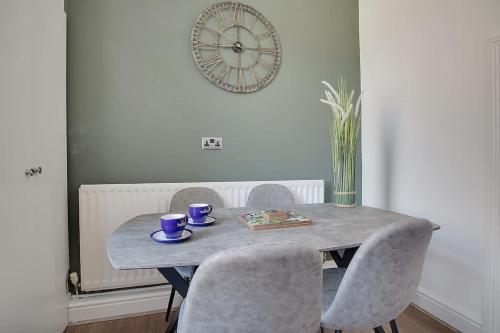 a dining room table with chairs and a clock on the wall at Stylish 3-Bedroom Oasis in Darlington, Sleeps 5 in Darlington