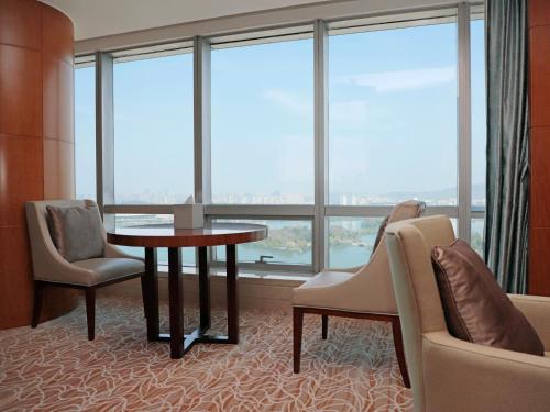 a hotel room with a table and chairs and windows at The Westin Nanjing Xuanwu Lake in Nanjing