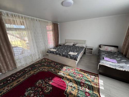 a bedroom with two beds and a rug at Center guesthouse in Kochkorka