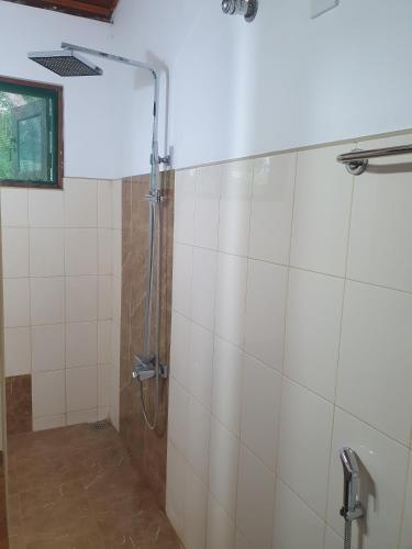 a shower in a bathroom with white tiles at Wilpattu Corridor Leisure in Wilpattu