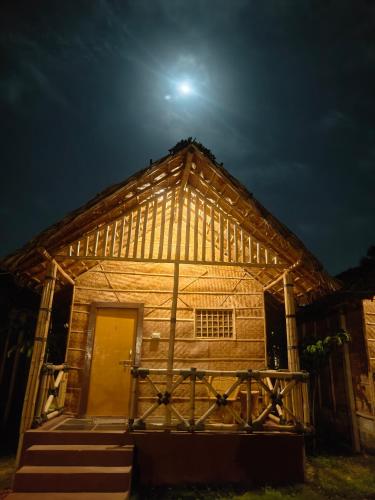 a wooden house at night with the moon in the sky at Crazzy Panda Hampi in Hampi