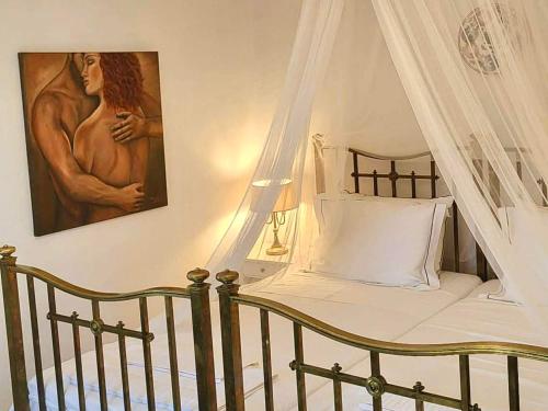 a bedroom with a canopy bed and a painting at Pepromeno Boutique in Agios Dimitrios