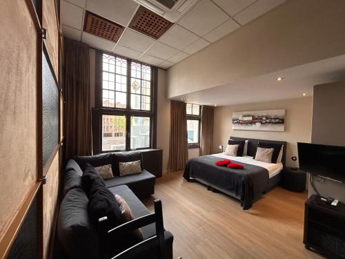 a bedroom with a bed and a couch and a tv at Amazing independent Studio S3, City Centre Dordrecht in Dordrecht