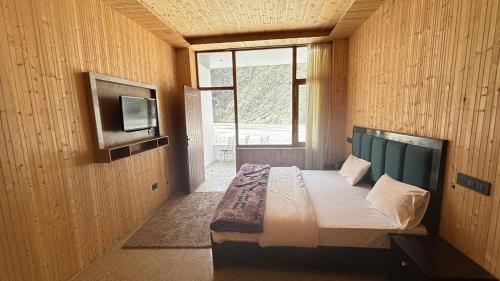 a bedroom with a bed with a tv on the wall at Harsil River Retreat in Harsil