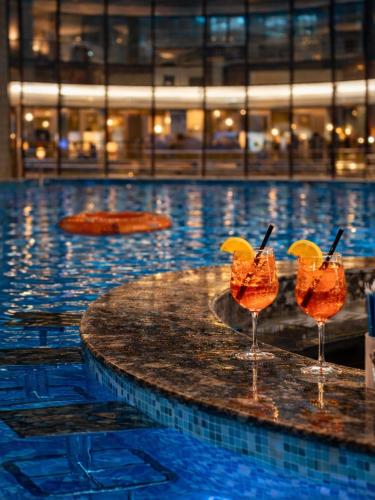 two cocktails on a table in a swimming pool at Hotel Piatra Mare in Poiana Brasov