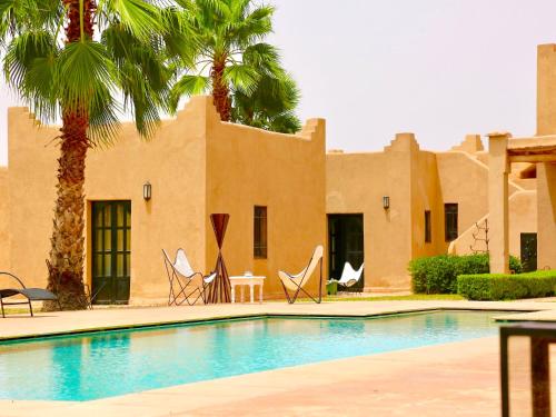 a pool in front of a building with palm trees at Palais Nova in Marrakesh