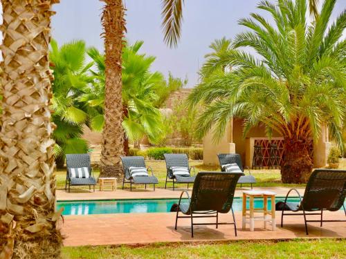 a group of chairs and a pool with palm trees at Palais Nova in Marrakesh