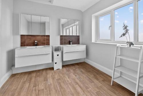 a white bathroom with two sinks and a window at The PADhouse in York