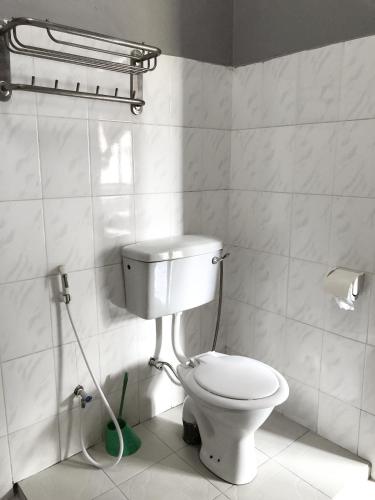 a bathroom with a toilet and a green mop at Kiusa Badget Hotel in Moshi