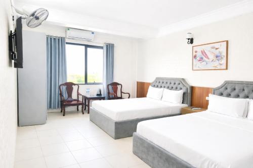 a hotel room with two beds and a table and chairs at Bạch Tuyết Hotel in Cửa Lô
