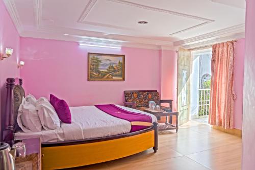 a bedroom with pink walls and a bed in a room at Hotel Mount View in Kodaikānāl
