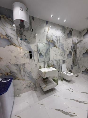 a bathroom with a marble wall with a sink and a toilet at درة القيم in Taif