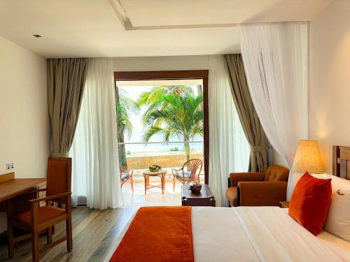 a hotel room with a bed and a desk and a window at Travellers Beach Hotel & SPA in Mombasa