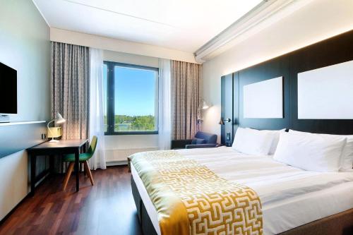 a hotel room with a large bed and a desk at Scandic Ruoholahti in Helsinki