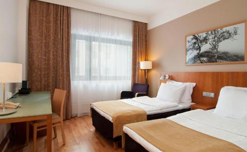 a hotel room with two beds and a desk at Scandic Veromies in Vantaa