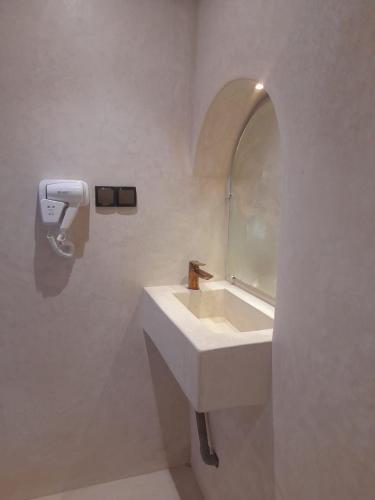 a white bathroom with a sink and a mirror at Riad NACIRIA in Aït Ourir