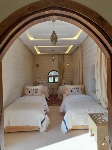 two beds in a room with an archway at Riad NACIRIA in Aït Ourir