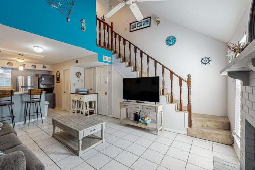 a living room with a staircase with a flat screen tv at Leeward Cove B4 in Padre Island